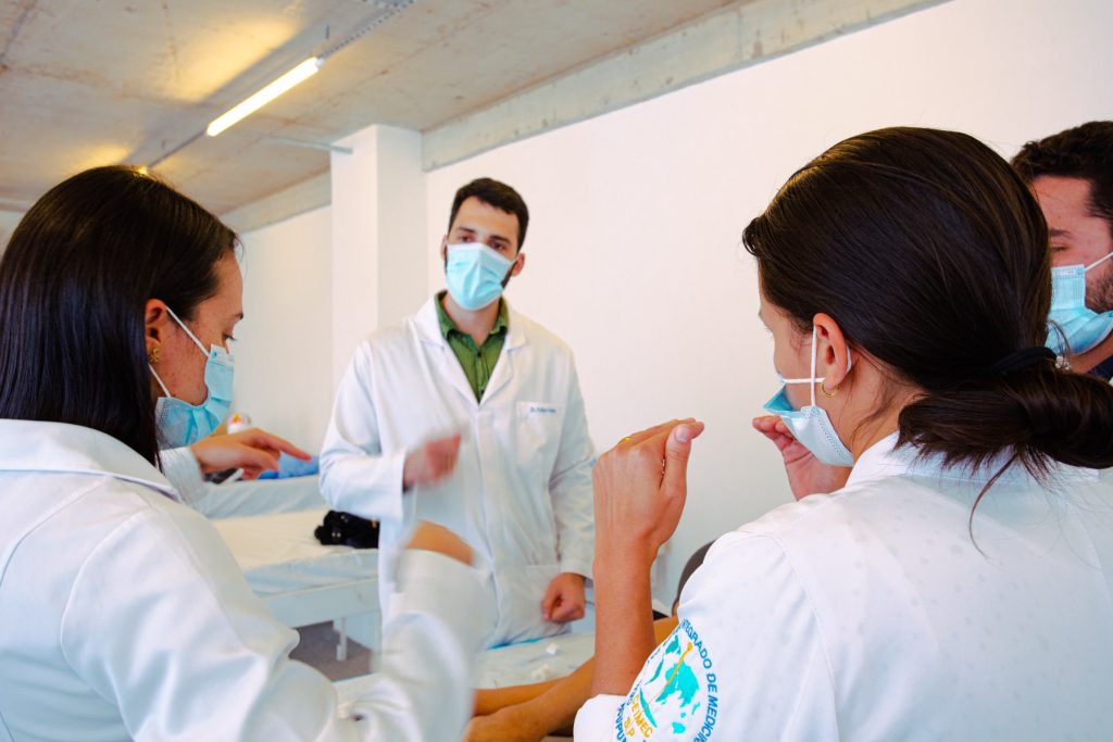 Docente orienta médicos em pequeno grupo na sala de prática do CEIMEC